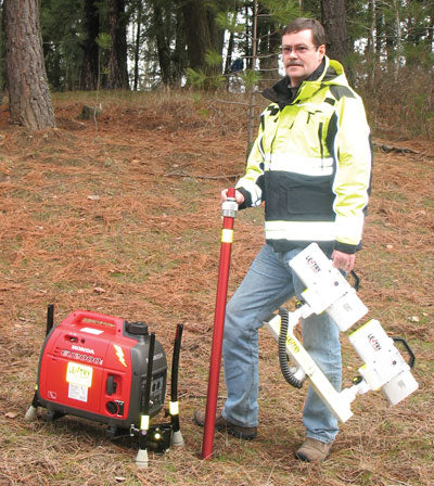 Lentry Lighting System Model 2TWSPX-C50 shown disassembled and ready for transport or storage. James stands next to the generator/legs portion while holding the XT height pole and 2-Headed LED light head. Case not shown.